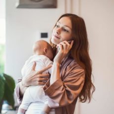 Eine junge Mutter informiert sich am Handy über Minijobs in Elternzeit