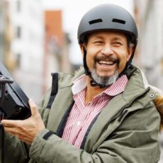 Ein Minijobber tauscht fröhlich den Akku seine E-bikes