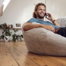 Mann sitzt auf einer Couch und telefoniert