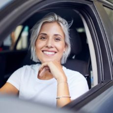 Frau sitzt im Auto und lächelt