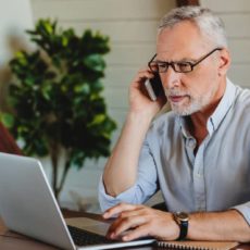 Man sitzt am Laptop und telefoniert