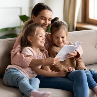 Haushaltshilfe liest Kindern etwas aus einem Buch vor