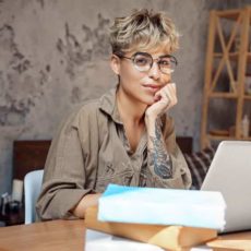 Frau sitzt am PC und guck in die Kamera