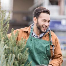 Mann verkauft an eine Frau einen Tannenbaum