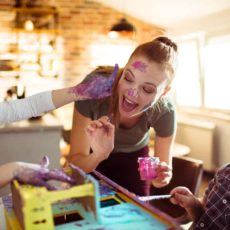 Kinderbetreuerin und Kinder spielen mit Fingerfarben