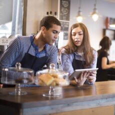 Zwei junge Baristas arbeiten mit einem digitalen Tablet.