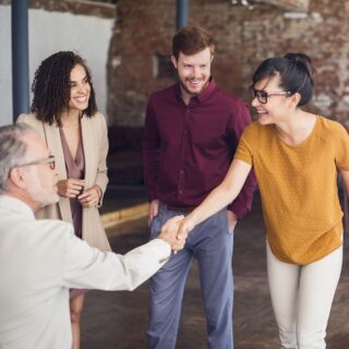 Ein Gruppe von Leute begrüßen sich mit Handschlag im Büro.